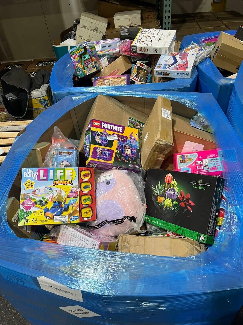 Blue wholesale toy pallet bin containing LEGO Fortnite game sets and boxed toys