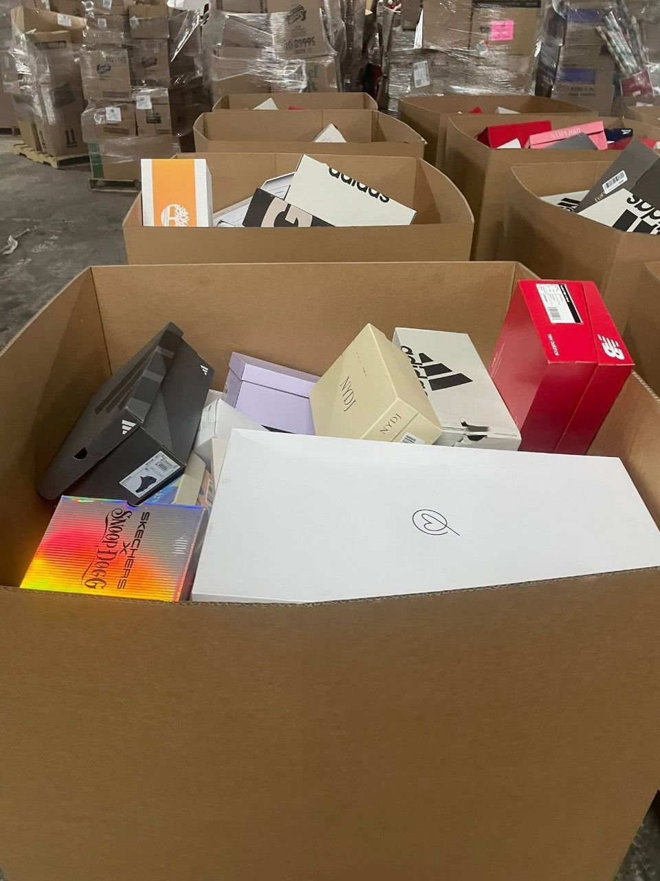 Multiple cartons of wholesale branded shoes and mixed shoe-box stock at warehouse