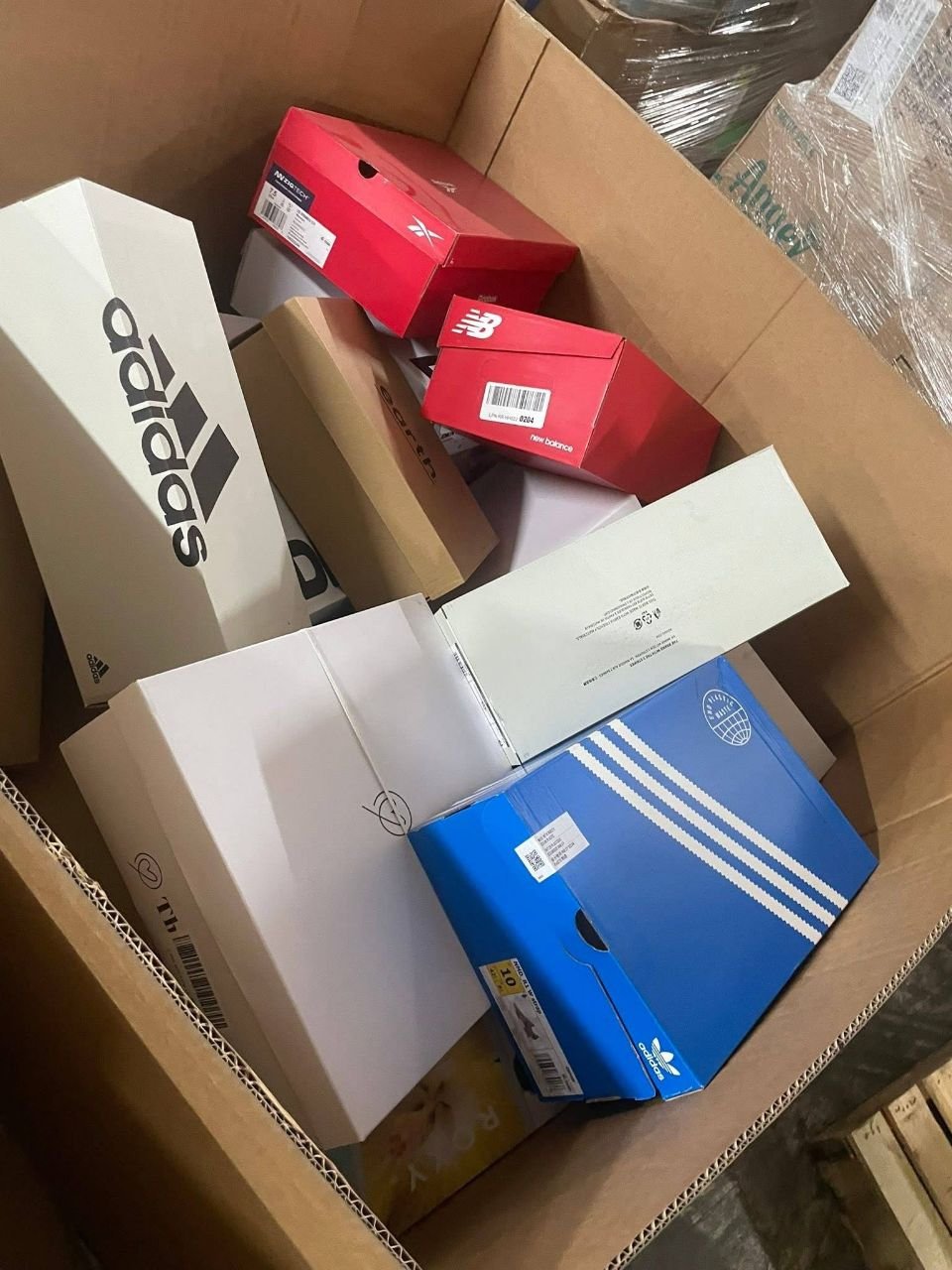 Mixed shoe pallet featuring blue adidas box and New Balance boxed footwear