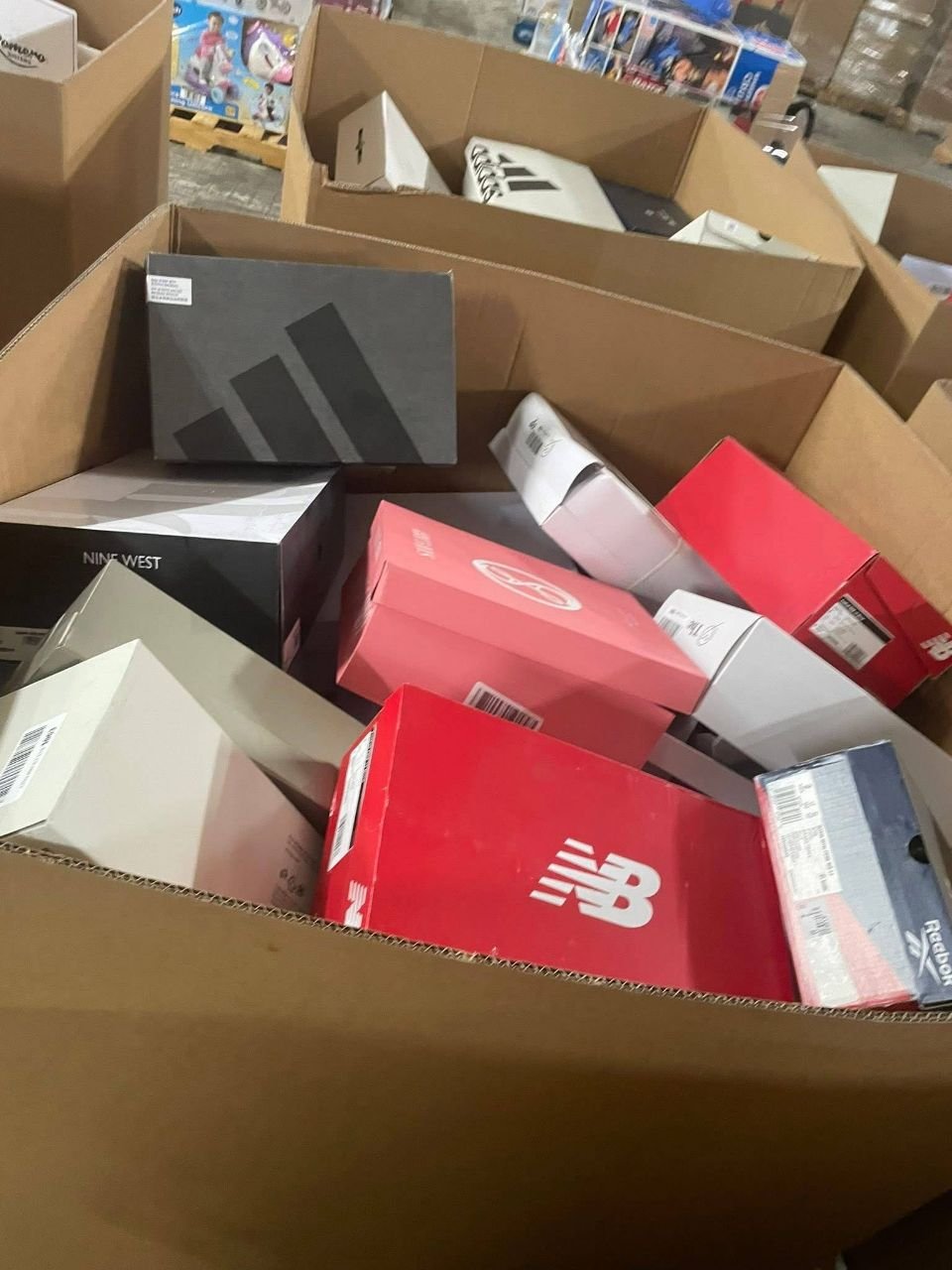 Shoe liquidation pallet showing adidas and New Balance branded shoe boxes in bulk cartons