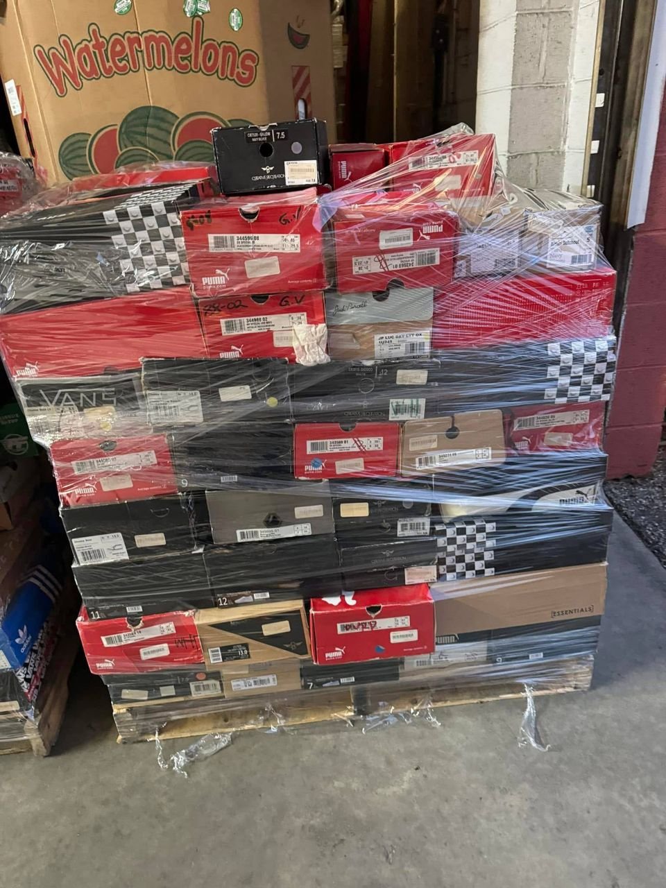 Pallet of assorted shoe boxes with prominent Puma and Vans footwear packaging