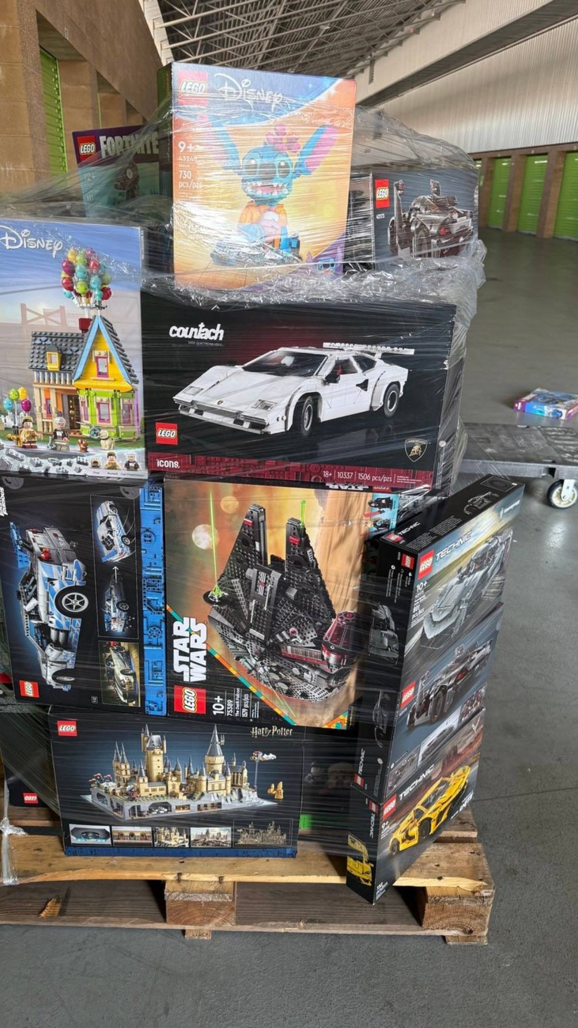 Stacked LEGO toy sets on shipping pallet showing Disney and assorted building kits