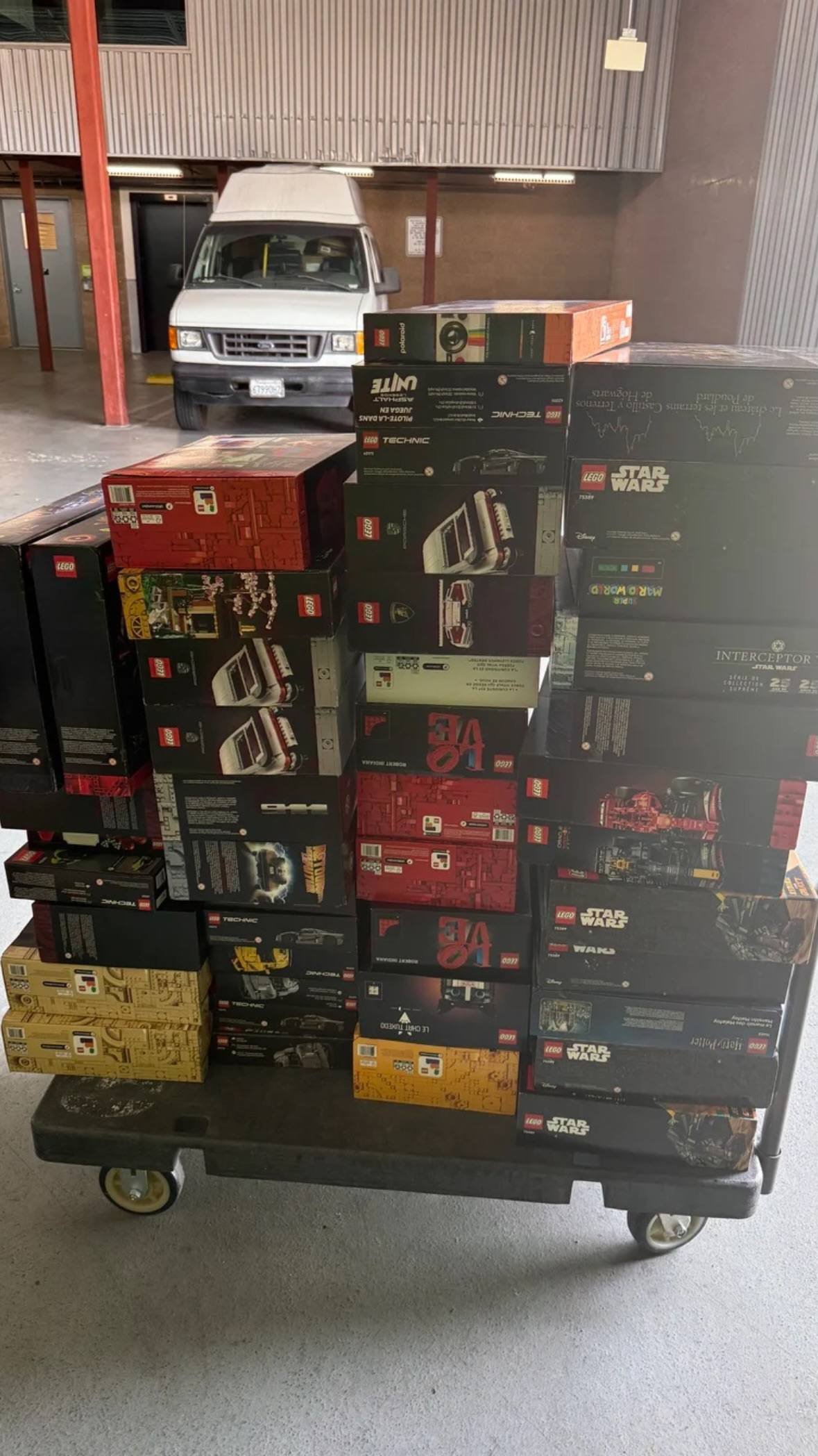 Bulk original LEGO boxed toy sets displayed on loading trolley in warehouse